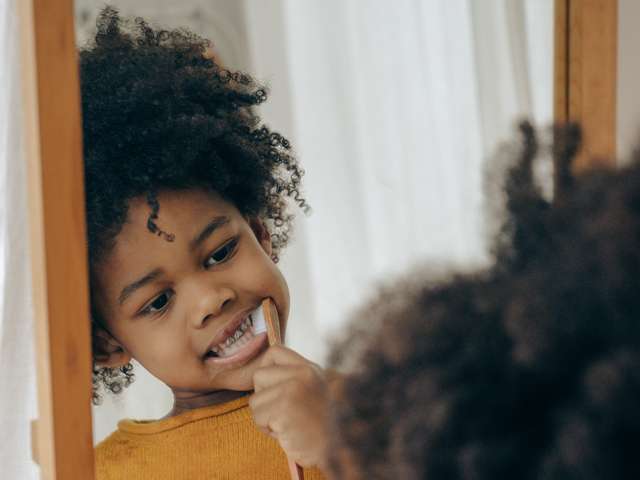 dr. dennis dunne, african-american-kid-cleaning-teeth-looking-in-mirror